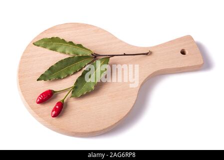 Essiccato l'alloro e peperoncino su una lastra di legno Foto Stock