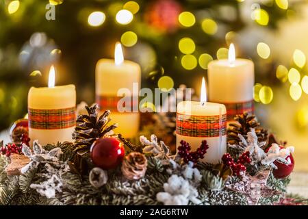Corona di avvento con quattro bianchi candele accese palla di Natale e decorazioni su uno sfondo di legno con atmosfera festosa Foto Stock