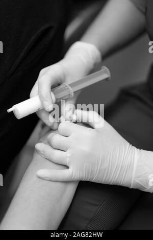 Le mani di un medico che la preparazione di un paziente per la somministrazione endovenosa del farmaco attraverso un catetere Foto Stock