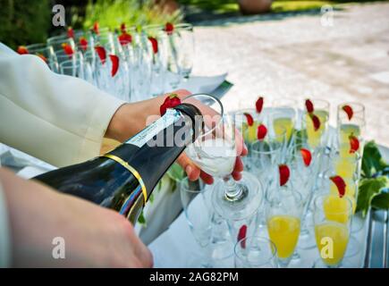 Champagne versando in bicchieri da una bottiglia Foto Stock