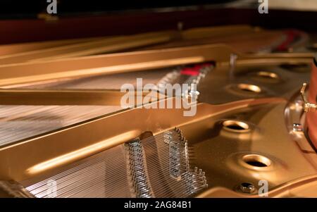 Primo piano della parte interna di un pianoforte dorato con corde d'argento Foto Stock