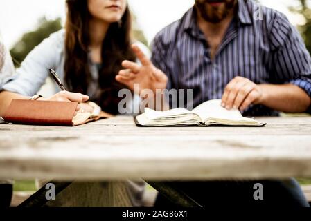 Primo piano di una coppia seduta nel parco e. leggere la bibbia con uno sfondo sfocato Foto Stock