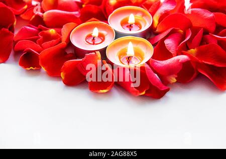 Candele accese in petali di rosa. Lay piatto. Spazio di copia Foto Stock