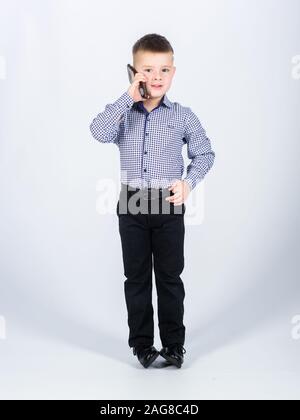 Gadget moderno. Piccolo imprenditore. Educazione e sviluppo. Bambino abiti formali di chiamata del telefono mobile. Ragazzo carino tenere lo smartphone. Conversazione Mobile. Business School. La comunicazione mobile. Foto Stock