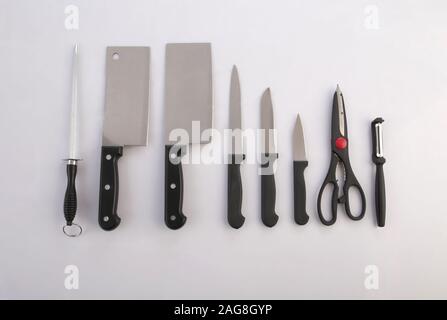 Un gruppo di coltelli da cucina, affilatori, forbici e pelapatate isolati su sfondo bianco Foto Stock