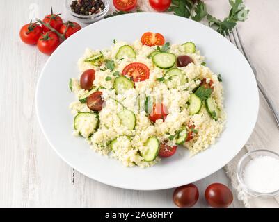 La dieta fresca insalata di verdure con cuscus, pomodori, cetrioli, prezzemolo, bianco tavolo in legno, vista laterale Foto Stock