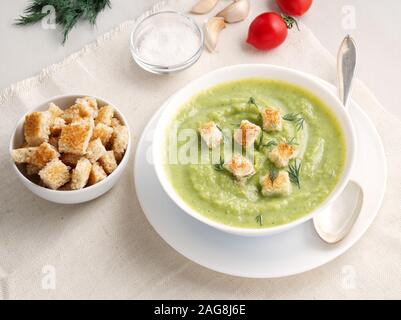 Grande ciotola bianca con verdura verde minestra in crema di broccoli, zucchine, piselli verdi su sfondo bianco, vista laterale Foto Stock