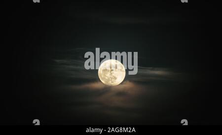 Luna piena impostazione sulle nuvole Foto Stock