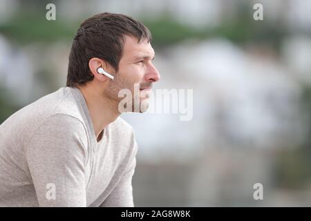 Vista laterale verticale di un uomo serio l'ascolto di musica con cuffie wireless Foto Stock