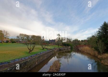 La piccola frazione di Lunan con il fiume che scorre attraverso di essa in una fredda mattina presto in dicembre, con riflessioni in acqua calma. Foto Stock