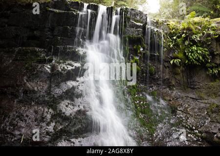 L'angolo basso di una bella cascata che cade dal formazione rocciosa in una foresta Foto Stock