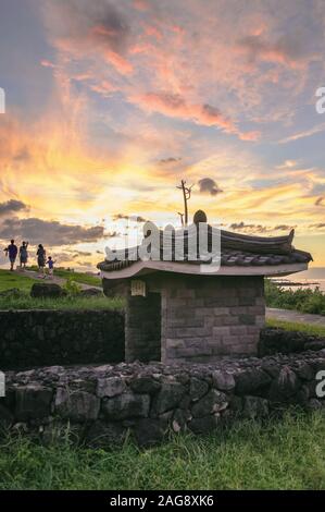 Jeju, Corea del Sud, settembre 09, 2019: la gente camminare verso Hamdeok spiaggia con incredibile tramonto sullo sfondo e tradizionale edificio coreana fatta di Foto Stock