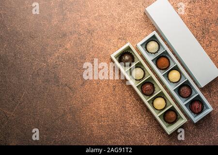 Cioccolatini fatti a mano in diverse caselle su uno sfondo scuro. Appartamento vista dall'alto. Telaio orizzontale copia spazio. Foto Stock