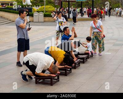 Nashan Cultural Park, HAINAN, Cina - 5 MAR 2019 - Asian buddista cinese devoti inginocchiati e sottomettono / archetto in preghiera alla Dea della Misericordia, Guanyin Foto Stock