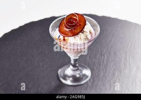 Un getto ad alto angolo di gelato in una tazza di vetro con un pezzo di prugna sulla parte superiore Foto Stock