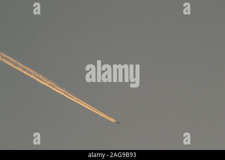 Bellissimo scatto di un aereo lasciando la sua traccia dorata dentro il cielo Foto Stock