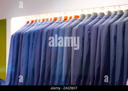 Una fila di uomini giacche su un appendiabiti in un negozio di abbigliamento Foto Stock