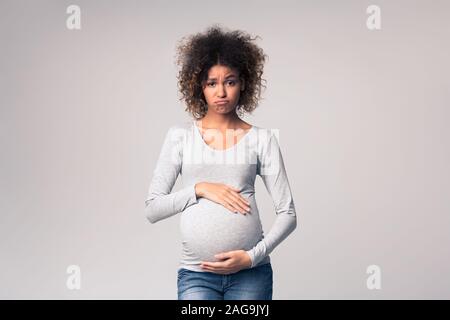 Ormoni e cambiamenti d'umore. Triste speranzosi donna toccando ventre Foto Stock