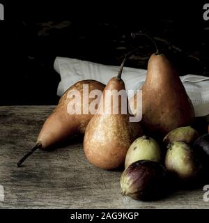 Fotografia di pere e fichi su un legno scrivania con sfondo nero Foto Stock