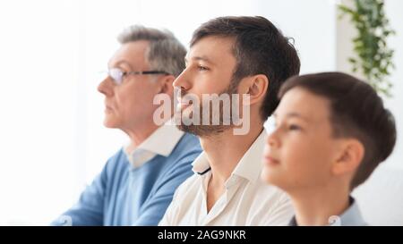 Coppia uomo seduto tra anziani padre e figlio piccolo indoor Foto Stock