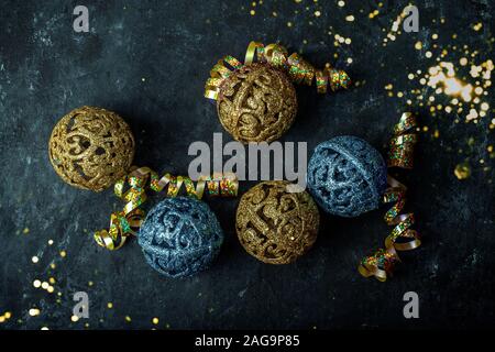 Anno nuovo Natale oro e palle blu su sfondo scuro con paillettes sparse Foto Stock