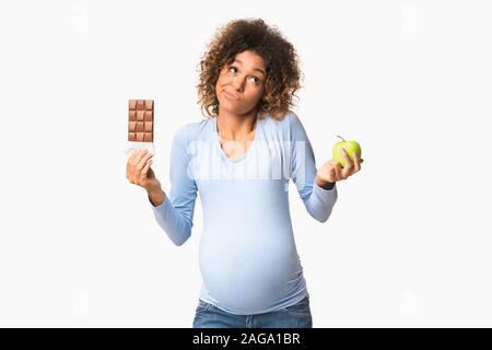 Perplesso aspetta donna scelta tra dolci e frutta Foto Stock