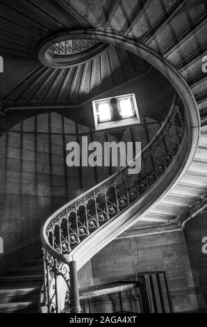 Immagine verticale in scala di grigi ad angolo basso di una scala in un antico edificio Foto Stock