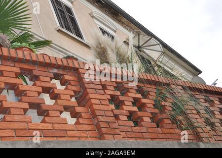 Multi-colore di recinzione in mattoni di ingresso della nuova casa - con lampadario circondato da fogliame Foto Stock