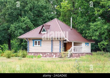 Una piccola casa di registro con un tetto triangolare nella parte anteriore della foresta Foto Stock