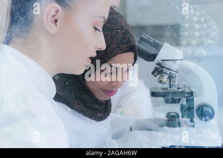Due società multietnica giovani femmine gli scienziati stanno svolgendo esperimenti in laboratorio. Lavorare in laboratorio con provette di prova o di ricerca in laboratorio clinico.Scien Foto Stock