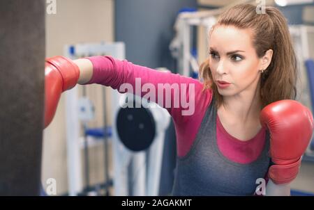 Boxer femmina di colpire un enorme sacco da boxe. Donna boxer attivamente la formazione e il disco. La difesa di auto e anti violenza della formazione Foto Stock