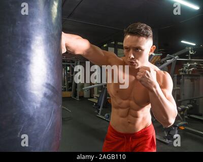 Boxer in formazione con il punzone bag in palestra. Uno stile di vita sano e la motivazione del concetto. Foto Stock