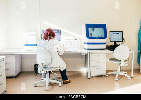 Kaliningrad, Russia il 15 ottobre 2019. Donna scienziato in camice bianco a lavorare in biologico o di laboratorio medico con DNA analyzer, preparazione al test del DNA Foto Stock