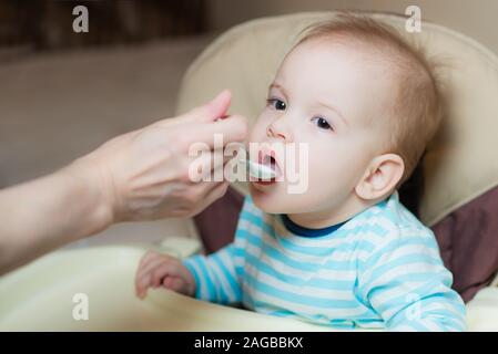 Baby a mangiare da un cucchiaio di latte mangia porridge Foto Stock