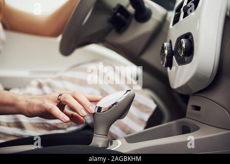 Vista ravvicinata della donna di mano sul bastone di marcia nella moderna industria automobilistica con interno bianco Foto Stock