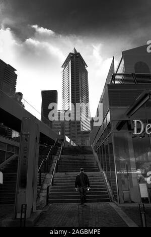 VANCOUVER, CANADA - Nov 13, 2019: una verticale in scala di grigi a bassa angolazione di una persona salendo una scala nel centro cittadino di Vancouver Foto Stock
