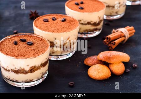 Tiramisù classico dessert in un vetro cosparso di cacao e decorate con i chicchi di caffè su uno sfondo scuro, dessert di lusso Foto Stock
