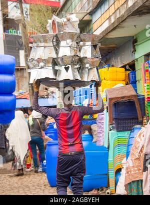 Un uomo Etiope locali di trasporto merci di stagno sulla sua testa nel mercato Merkato ad Addis Abeba in Etiopia che è il più grande Outdoor mercato all'aperto in Af Foto Stock