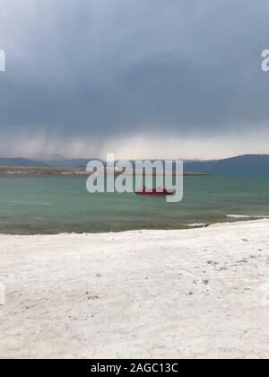 Scatto verticale di una persona sola che si addlona in rosso barca in mare sotto il cielo stollato Foto Stock