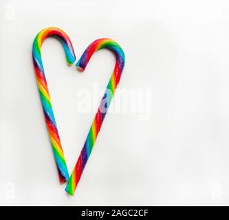 Due lecca lecca arcobaleno su sfondo bianco. Candy cuore. Sfondo di natale. Copia dello spazio. Foto Stock