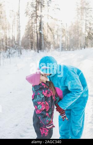 Immagine in primo piano verticale di una bambina carina che baciano a. donna in un morbido costume blu Foto Stock