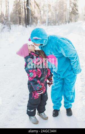 Immagine in primo piano verticale di una bambina carina che baciano a. donna in un morbido costume blu Foto Stock