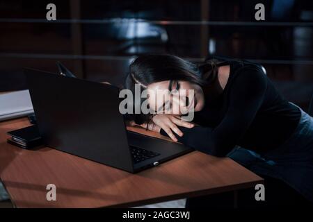 Appena si chiude gli occhi per un paio di minuti. Attraente brunette imprenditrice funziona solo in ufficio in notturna Foto Stock