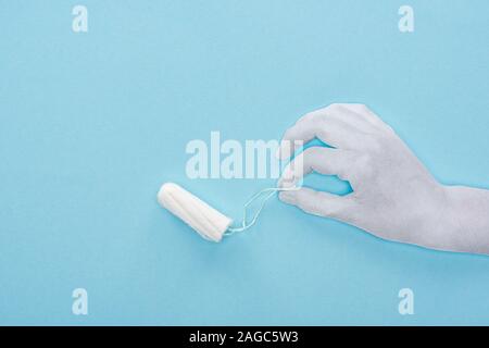Vista superiore della carta bianca tagliata mano azienda tampone di cotone su sfondo blu Foto Stock