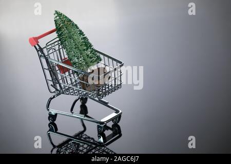 Angolo superiore vista del Mini albero di Natale all'interno piccolo carrello di shopping su sfondo argento Foto Stock