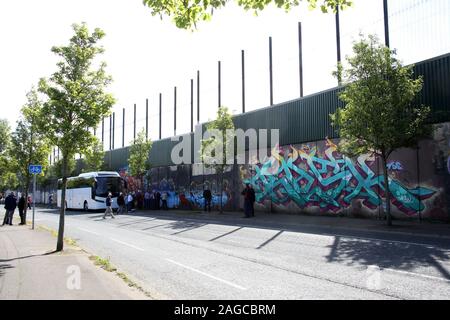 I turisti che visitano la colorati murali e i graffiti sulla parete di pace, o linea di pace, che corre lungo Cupar modo a Belfast. Si tratta di uno dei tanti separa Foto Stock