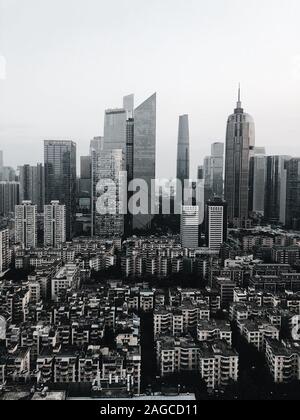 Immagine verticale in scala di grigi di un'area urbana con molti alti sorgono edifici di forme diverse Foto Stock