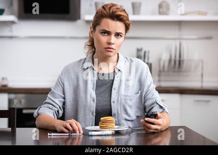 Donna con diabete Tenendo il glucosio monitor vicino pancake Foto Stock