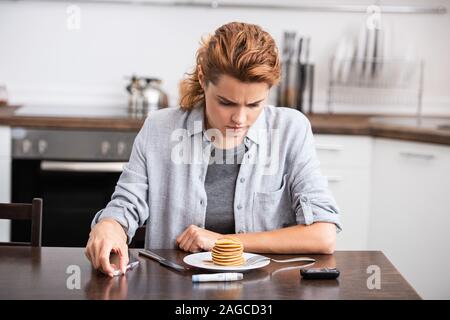 Donna con diabete guardando frittelle dolci Foto Stock