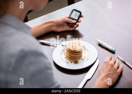 Messa a fuoco selettiva di donna con diabete Tenendo il glucosio monitor vicino pancake Foto Stock